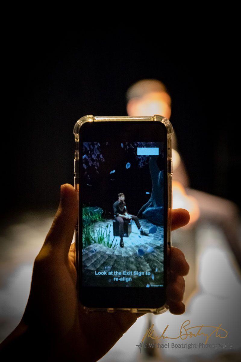 A phone reveals a digital figure layered over a live performer during The Safety Show